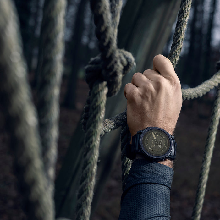A Garmin tactix 7 AMOLED tactical watch on the wrist of a hand climbing up a rope wall