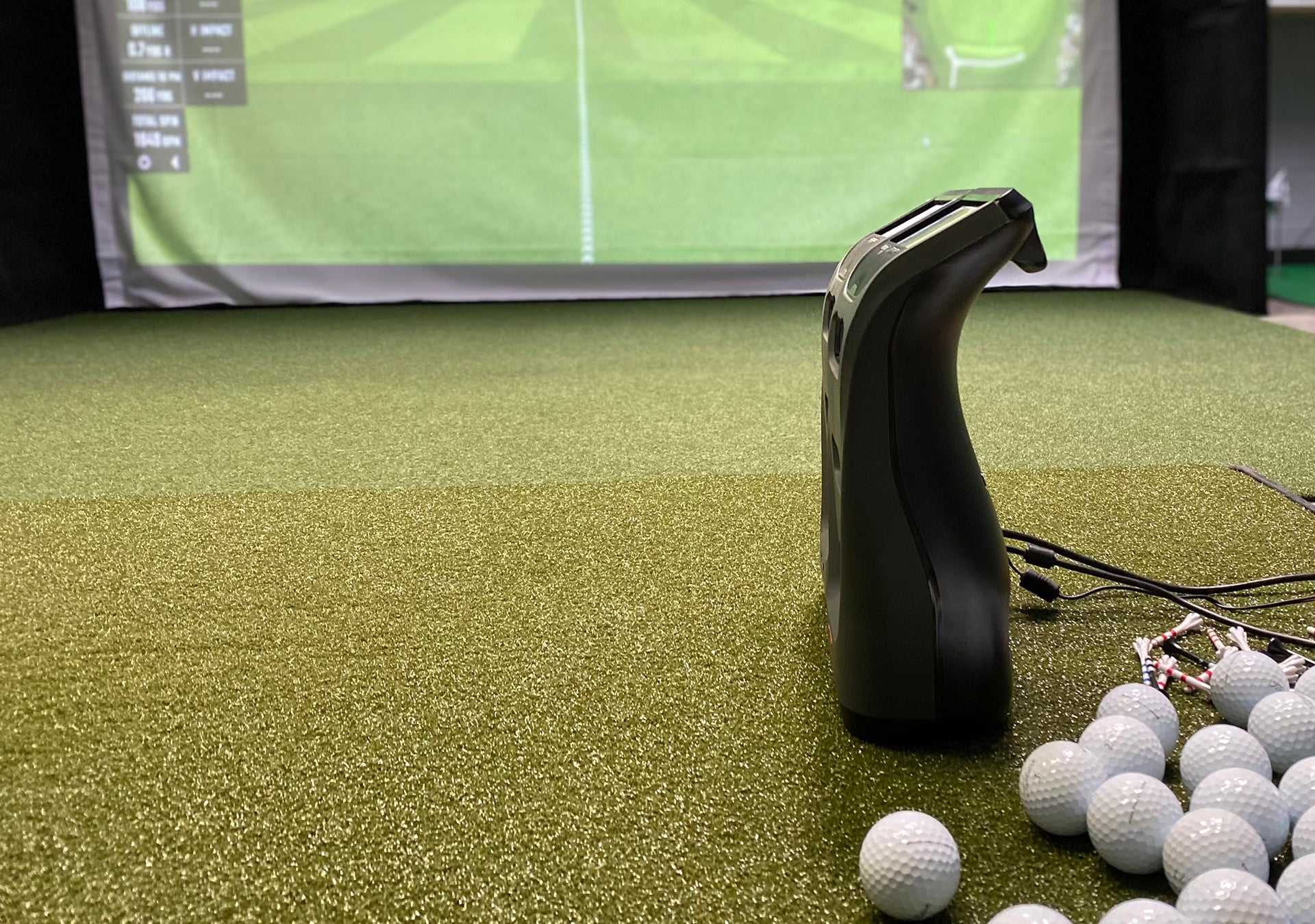 The Bushnell Launch Pro next to the Foresight GC3 in a golf simulator next to golf balls