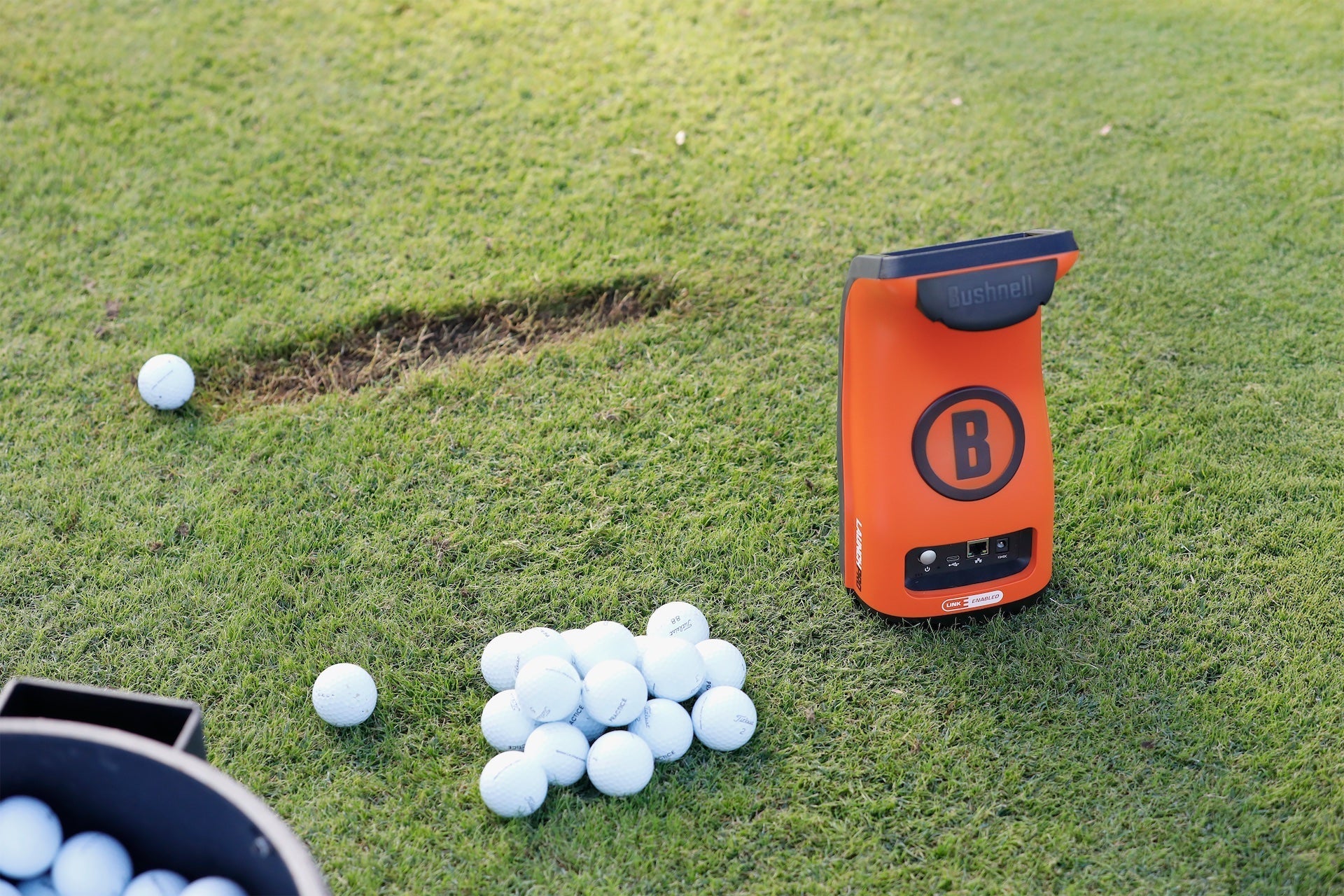 The orange back of the Bushnell Launch Pro Circle B Edition at the driving range