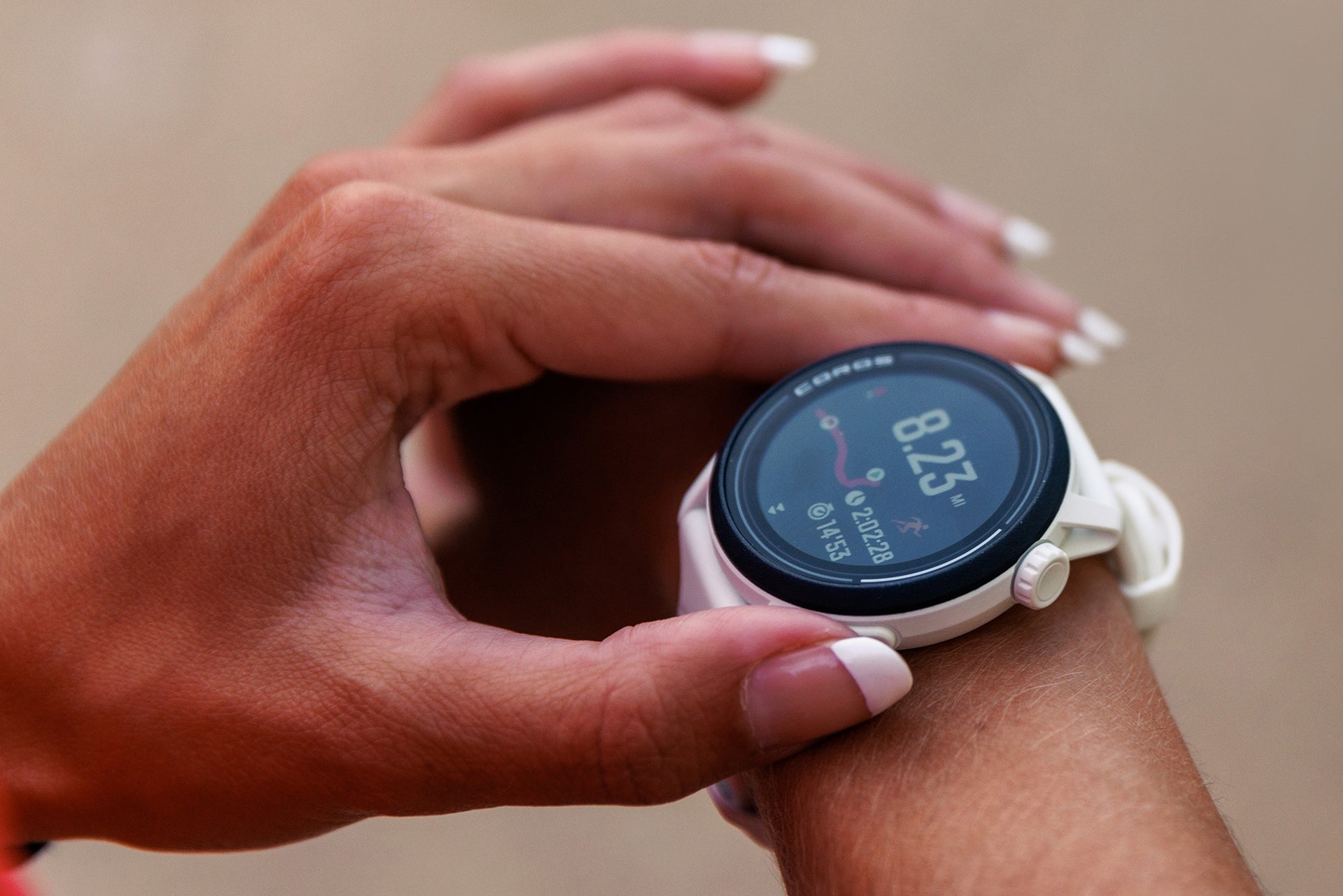 A closeup of a white COROS PACE 3 watch on a woman's wrist with her other hand adjusting the breadcrumb route on the display