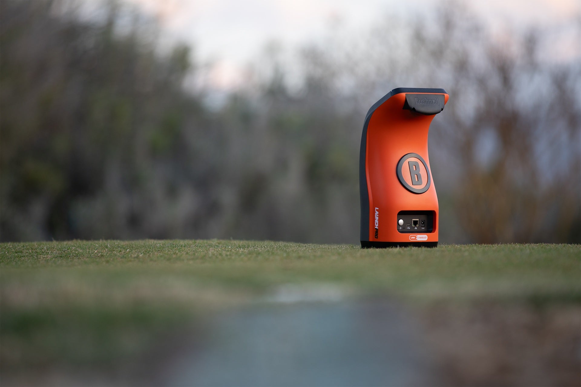 The orange rear backing of the Bushnell Launch Pro Circle B Edition launch monitor at the range