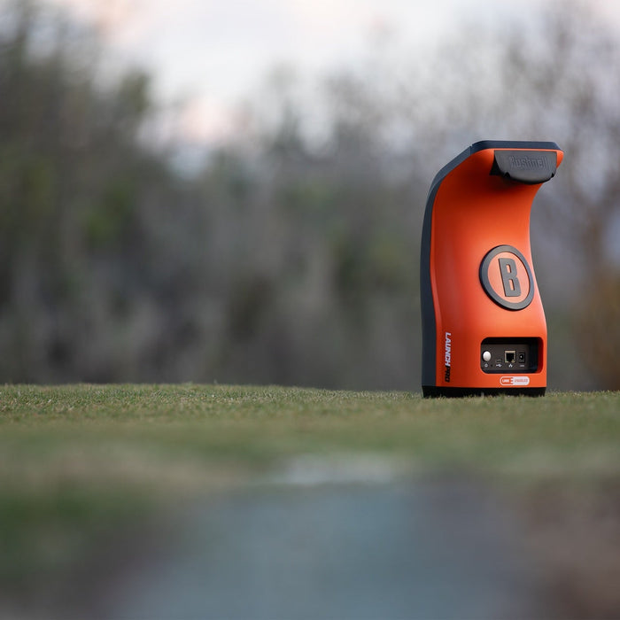 The orange rear backing of the Bushnell Launch Pro Circle B Edition launch monitor at the range
