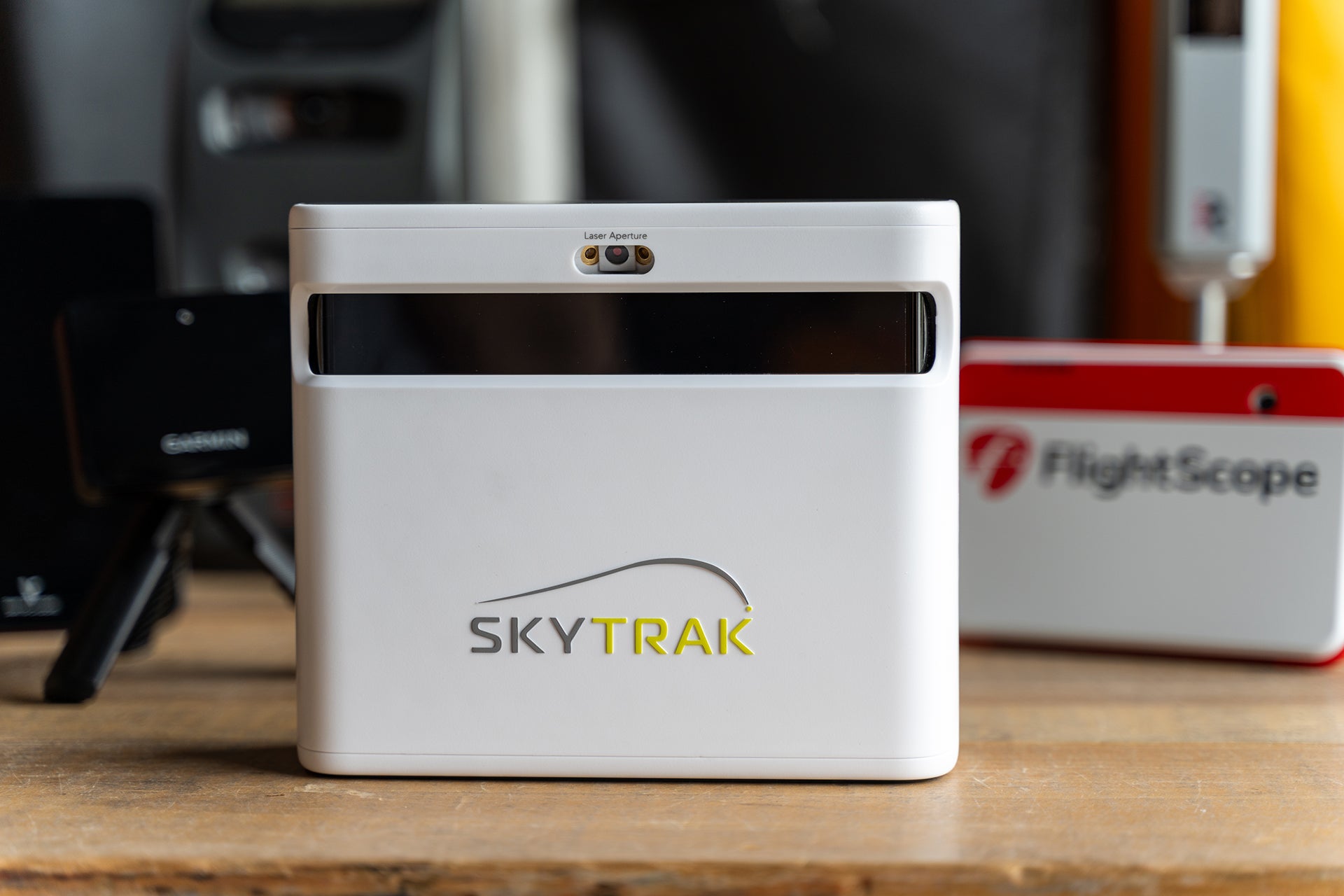 The SkyTrak+ golf launch monitor with other golf devices in the background 