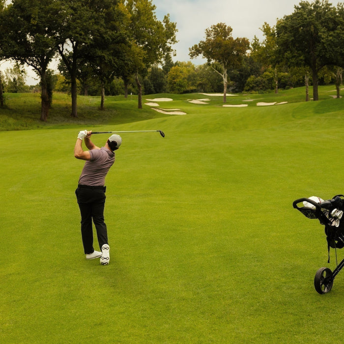 Golfer post swing hitting on a golf course with a golf bag push card