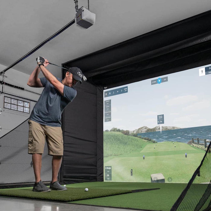 A golfer swinging in a Carl's Place golf simulator setup in a garage