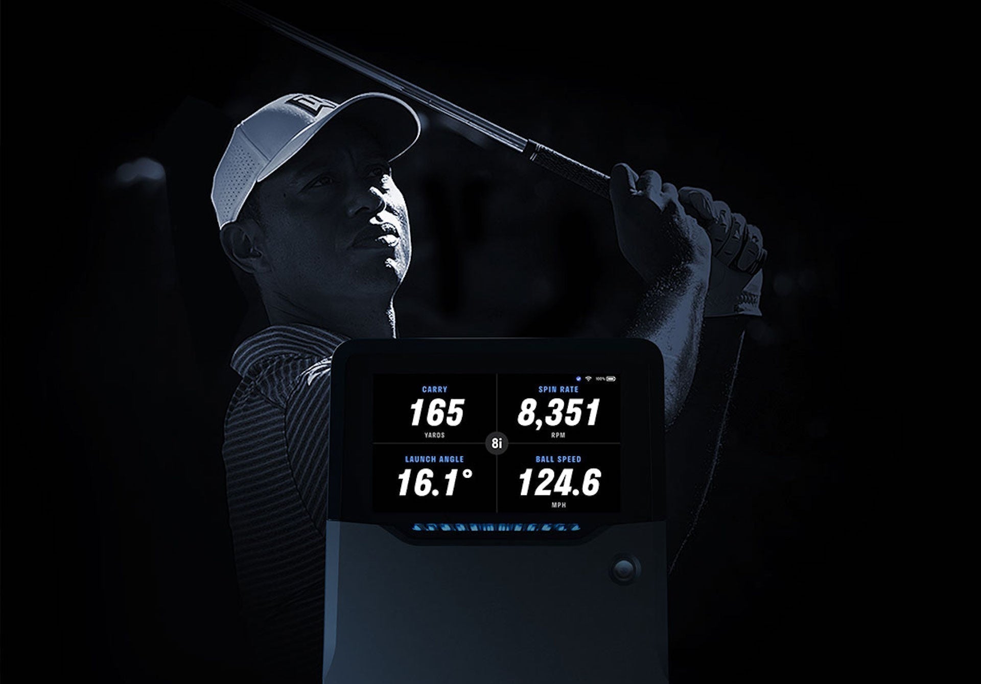 An image of Tiger Woods with a golf club over his shoulder behind a Full Swing KIT golf launch monitor with shot data on the built-in screen