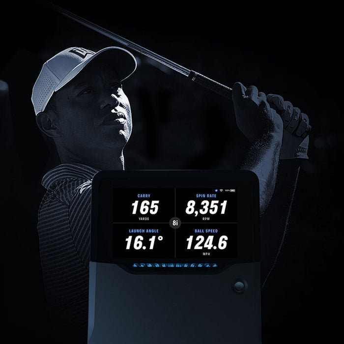 An image of Tiger Woods with a golf club over his shoulder behind a Full Swing KIT golf launch monitor with shot data on the built-in screen