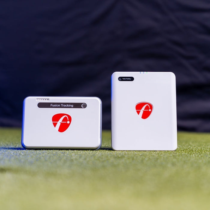 The FlightScope Mevo Plus next to the Mevo Gen2 on a golf hitting mat in a golf simulator