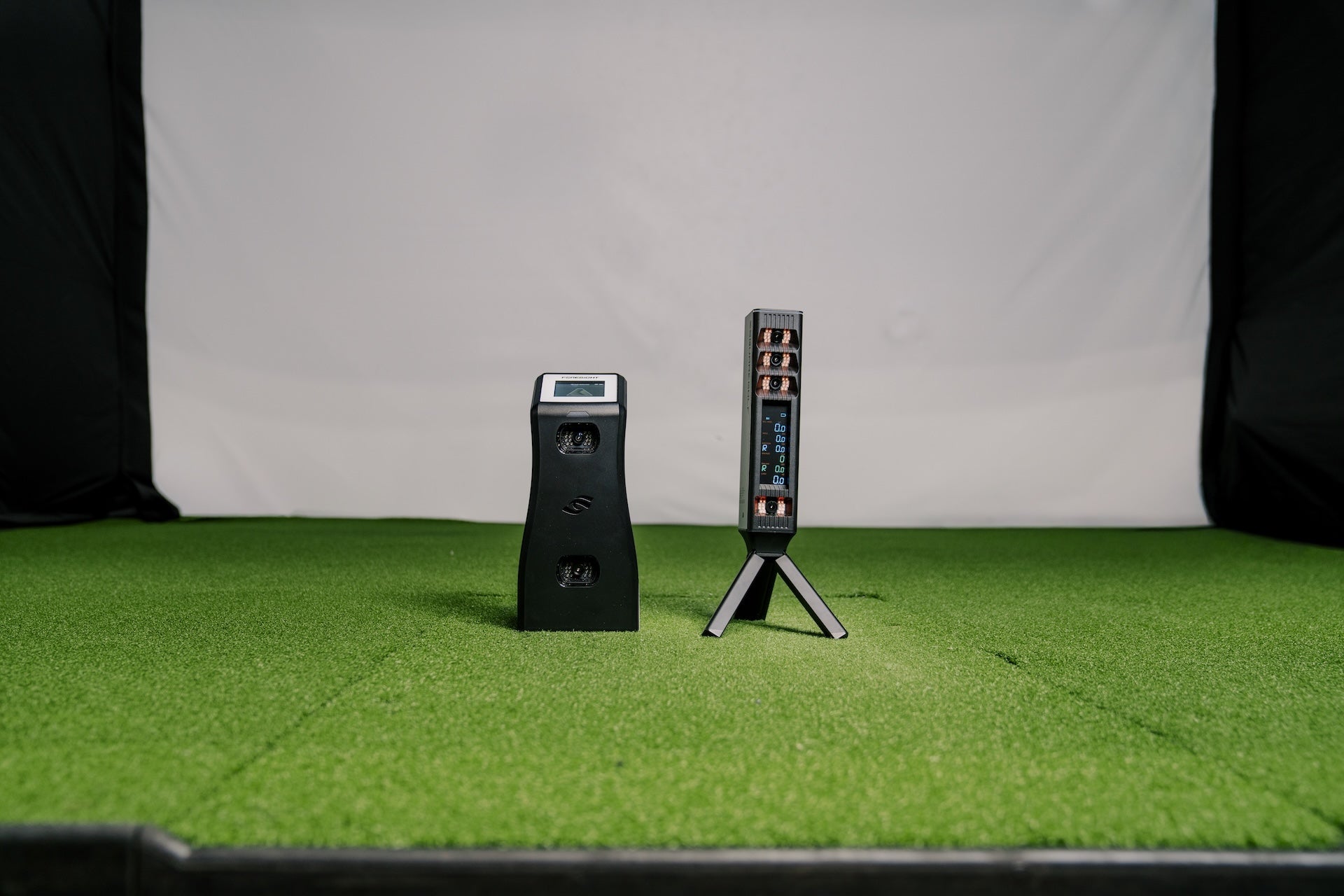 The Foresight Sports GC2 next to the Square Golf Omni golf launch monitors next to each other in PlayBetter's golf simulator