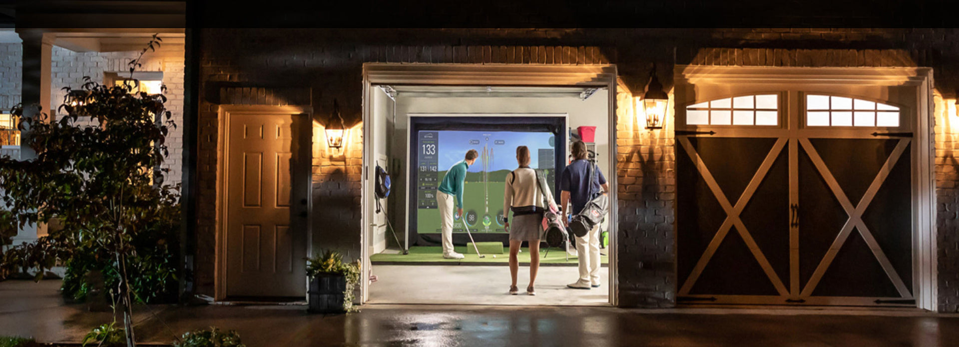 View from outside a double garage with two men watching another golfer hit into an impact screen in a garage golf simulator