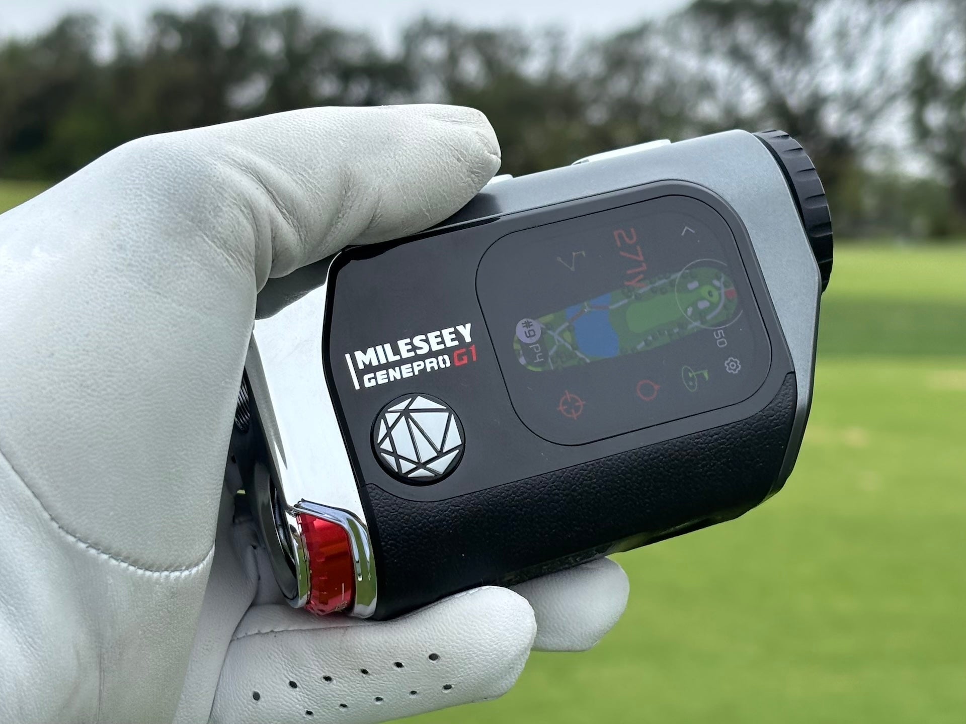 The Mileseey GenePro G1 GPS rangefinder in a golf-gloved hand at the golf course