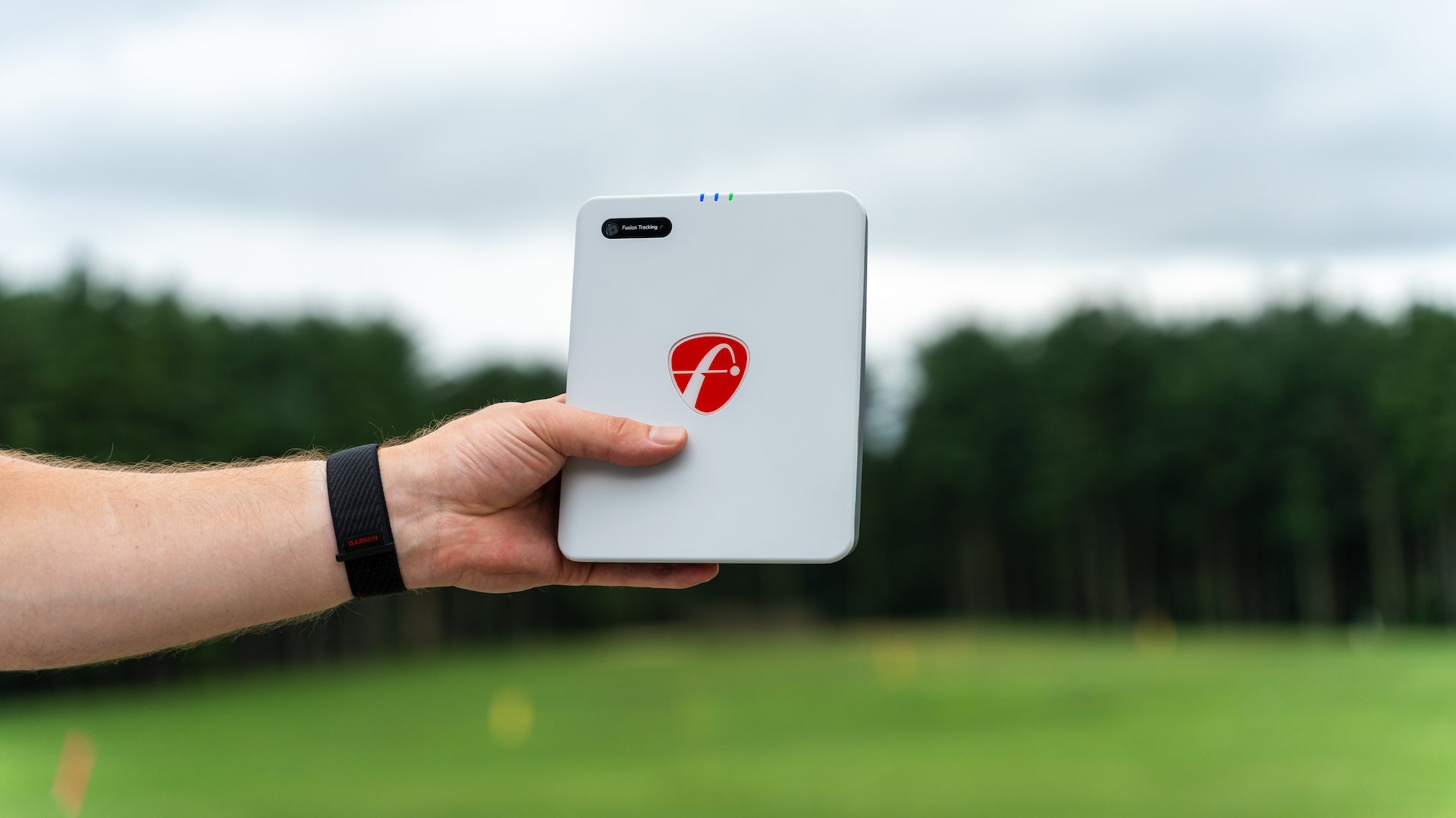 The FlightScope Mevo Gen2 held in a hand at the golf course