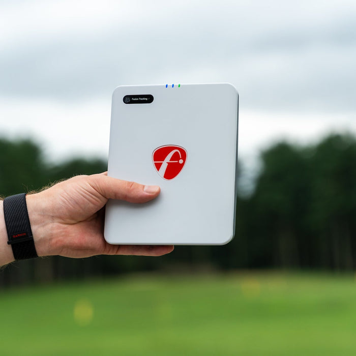 The FlightScope Mevo Gen2 held in a hand at the golf course