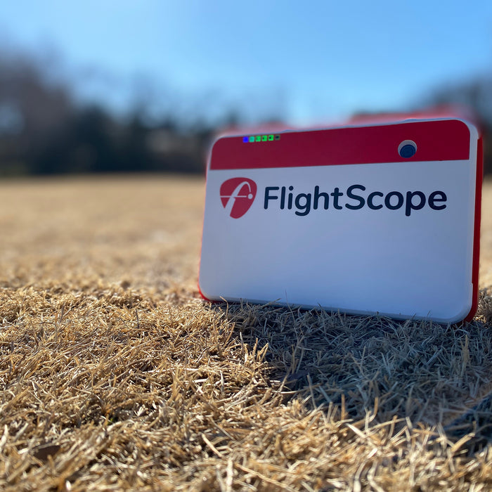 The FlightScope Mevo+ on tan winter golf course grass