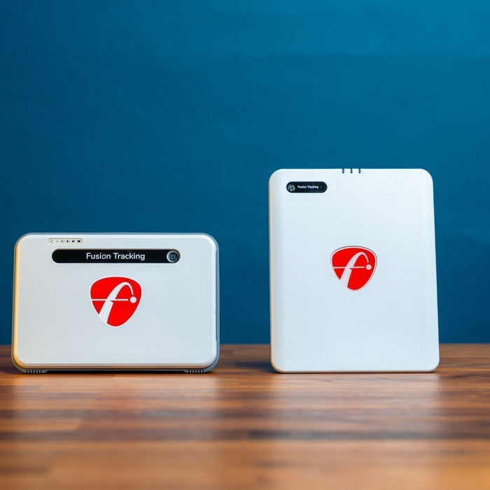 The FlightScope Mevo+ next to the new Mevo Gen2 golf launch monitor in front of a blue wall on a woodgrain surface