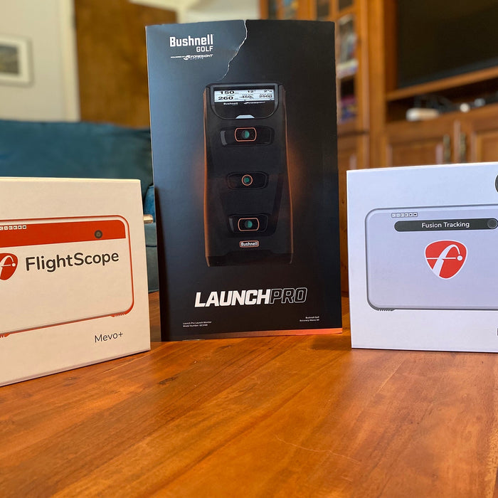 The Mevo+, Launch Pro, and Mevo+ Limited Edition in their standing in their boxes on a wooden table