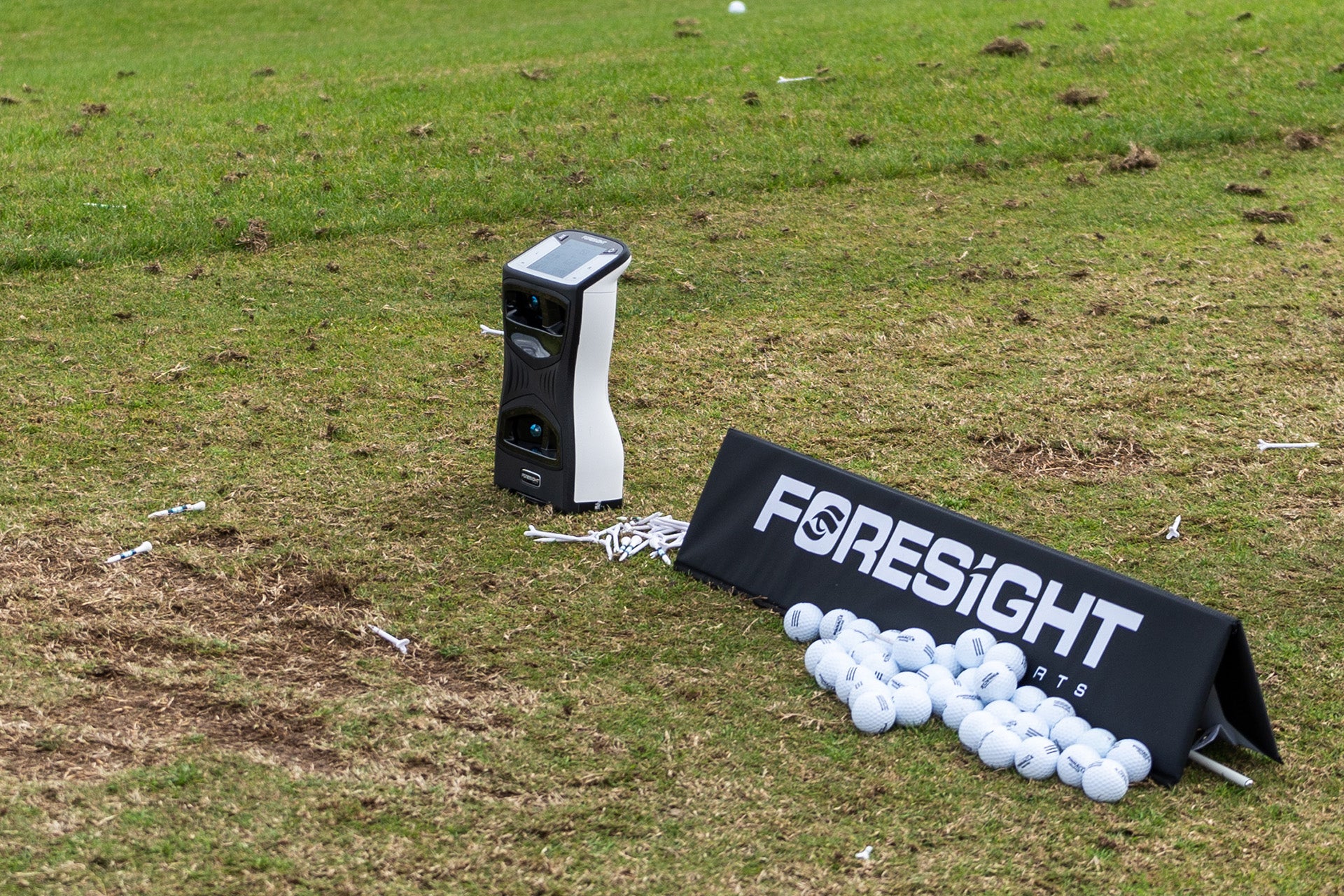 A Foresight Sports QuadMAX launch monitor next to a Foresight sign with golf balls and golf tees at the 2024 PGA show demo day range