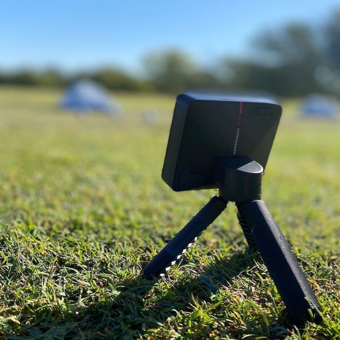 Rear-angled view of the Garmin Approach R10 golf launch monitor on its tripod on the golf range
