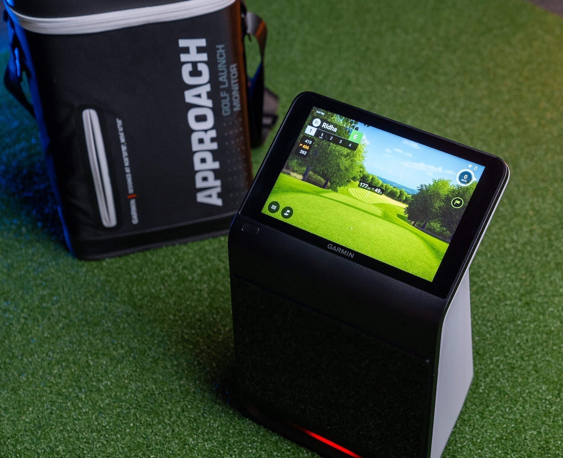 The Garmin Approach R50 golf launch monitor with Home Tee Hero simulator software on the display and the carrying case behind it on a golf hitting mat