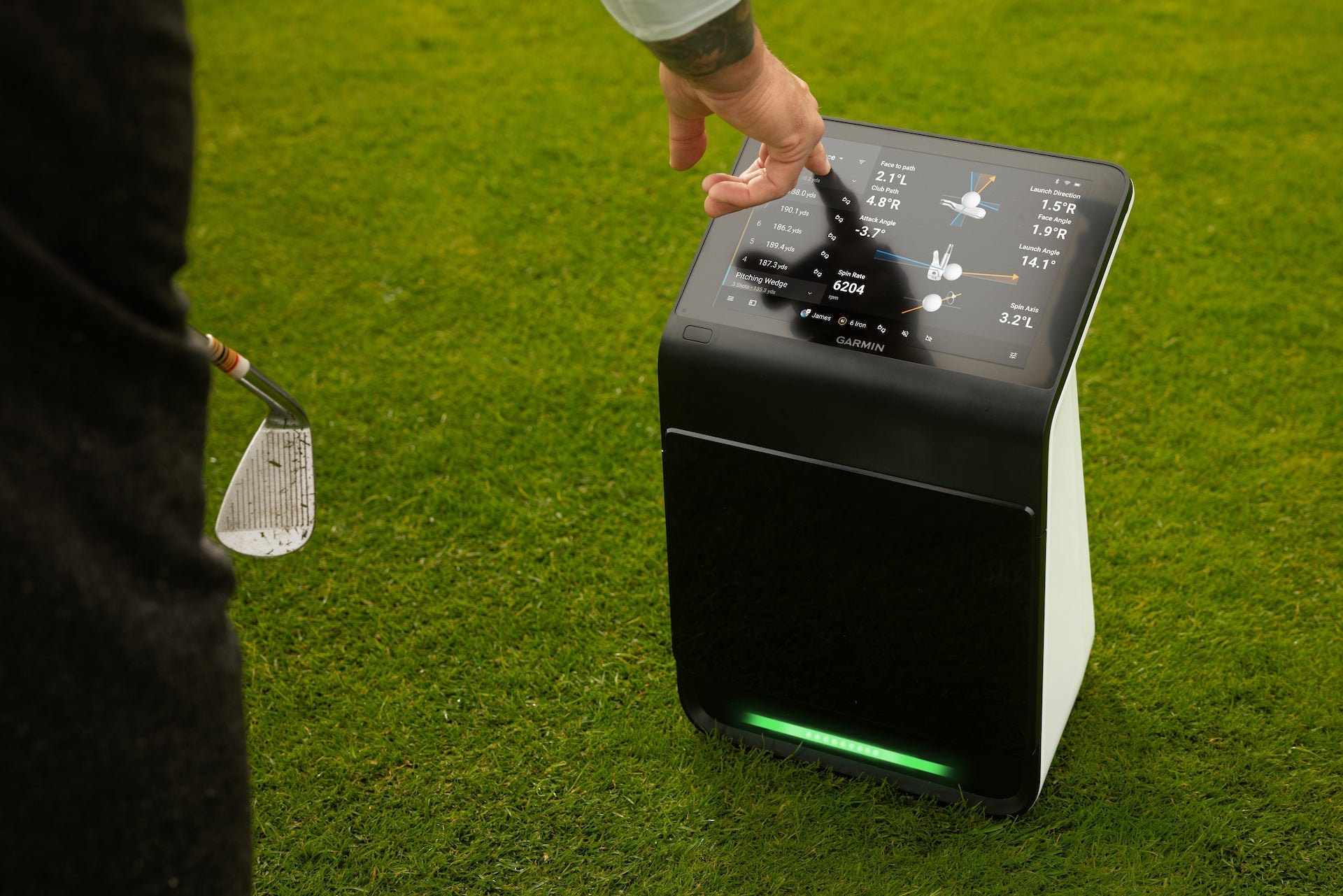 A golfer tapping the data on the touchscreen display of the Garmin Approach R50 on the golf course