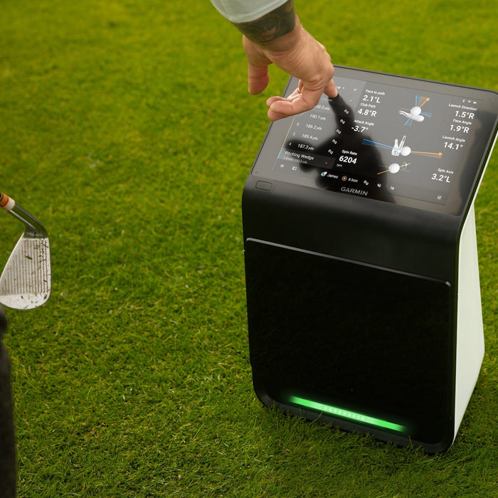 A golfer tapping the data on the touchscreen display of the Garmin Approach R50 on the golf course