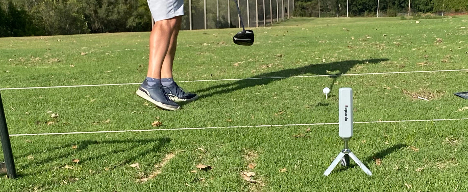 Legs of our golf guy, Marc, and the Rapsodo MLM2PRO during a swing at the golf range