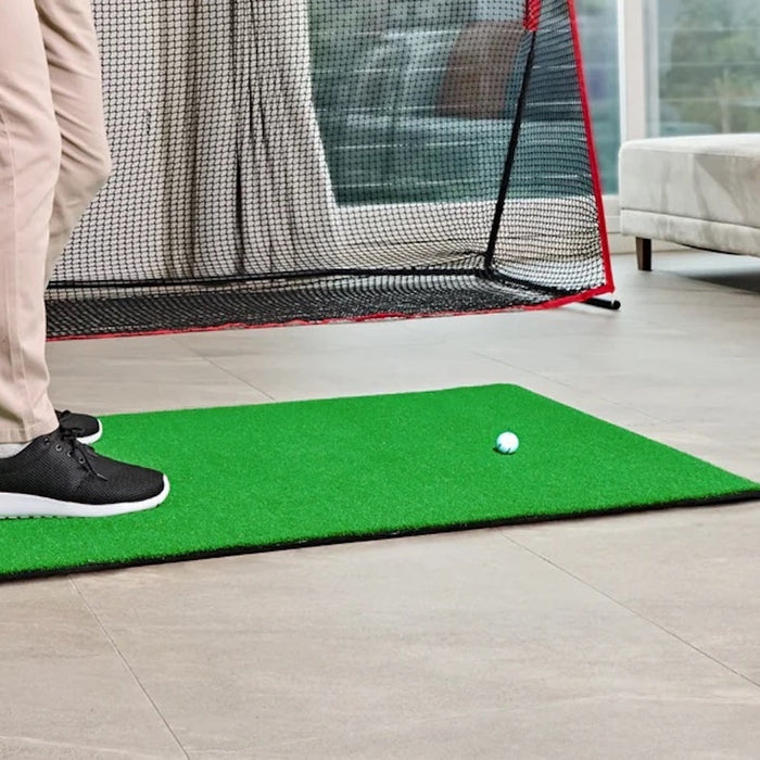 The lower half of a golfer getting ready to swing in a home golf setup in a living room with Swing Caddie SC4 Pro, golf hitting mat and golf net
