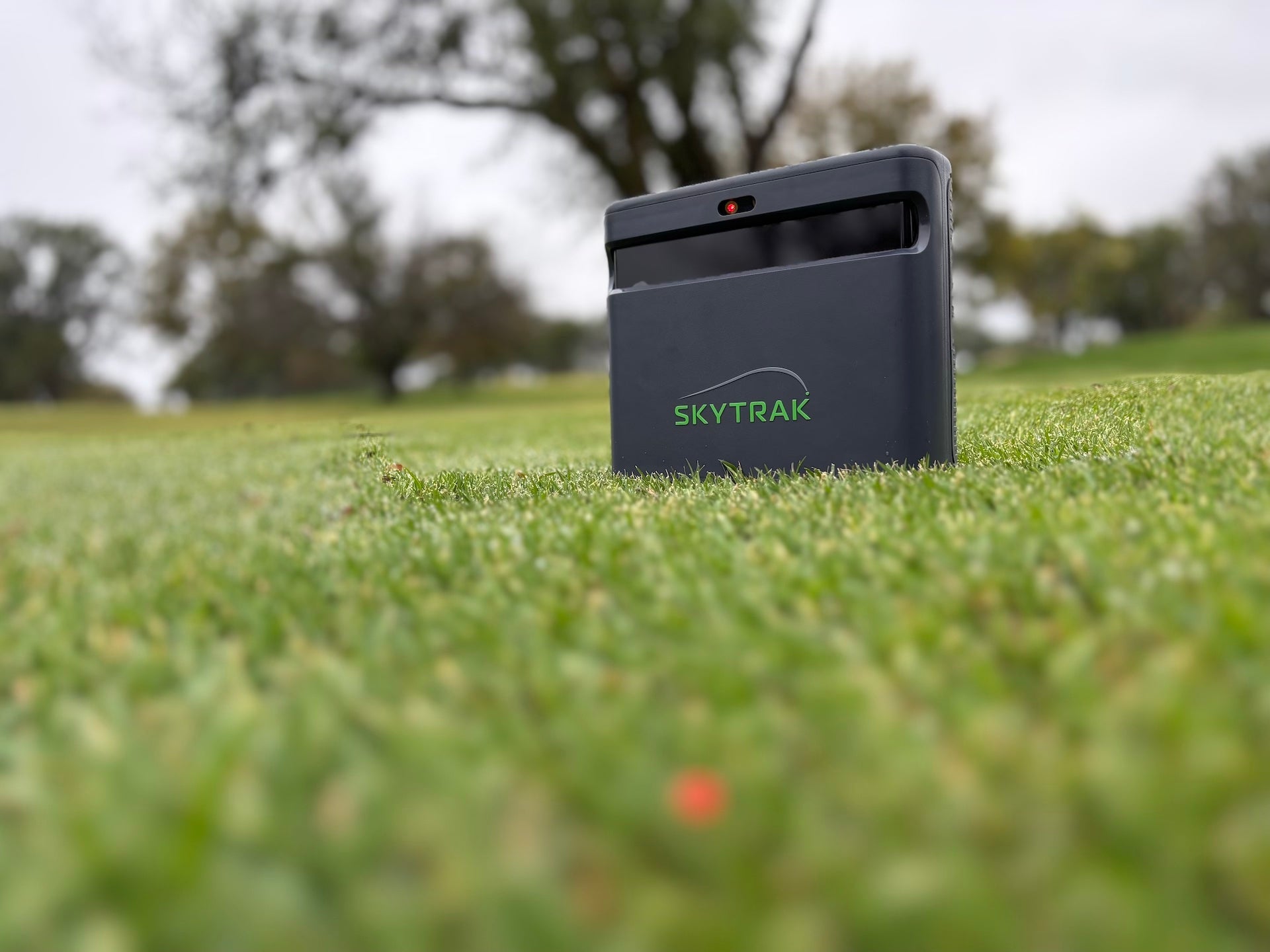 The SkyTrak ST MAX golf launch monitor on the grass at the golf course