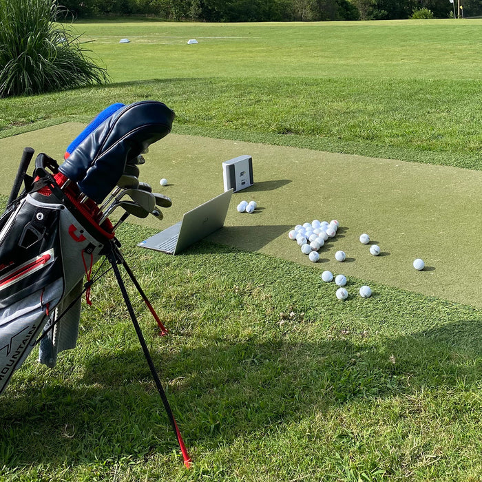 Golf reviewer Marc's golf bag, golf balls, laptop, and SkyTrak+ sitting at the golf range 