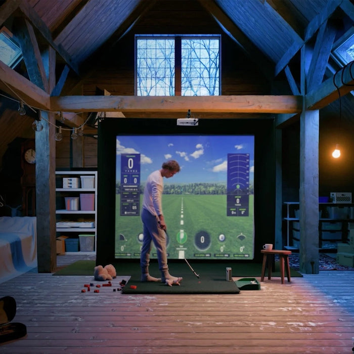 Golfer in a cool attic Skytrak golf simulator with virtual golf software on the golf impact screen