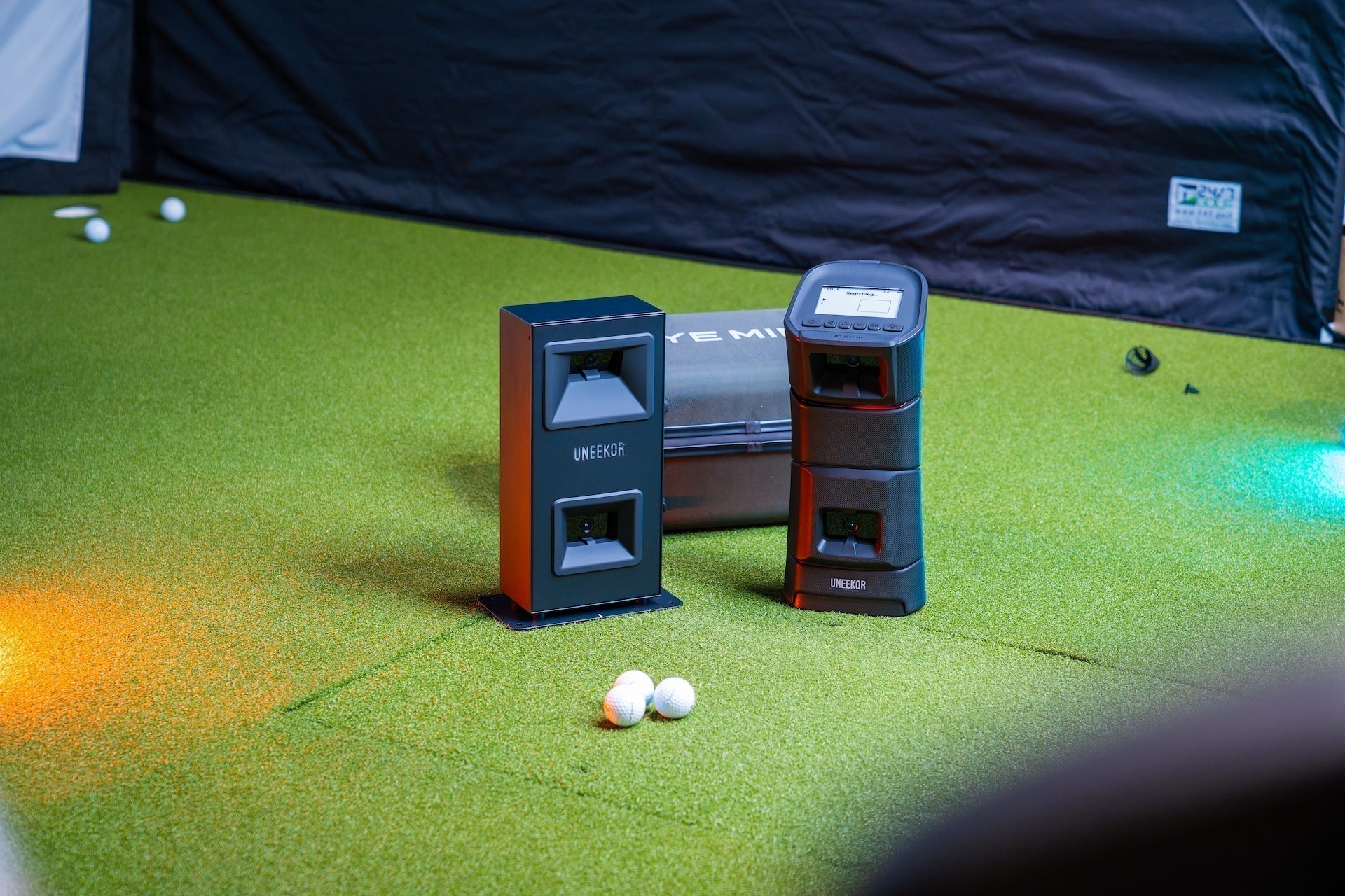 Uneekor Eye Min Lite and Eye Mini golf launch monitors next to each other in the PlayBetter golf simulator