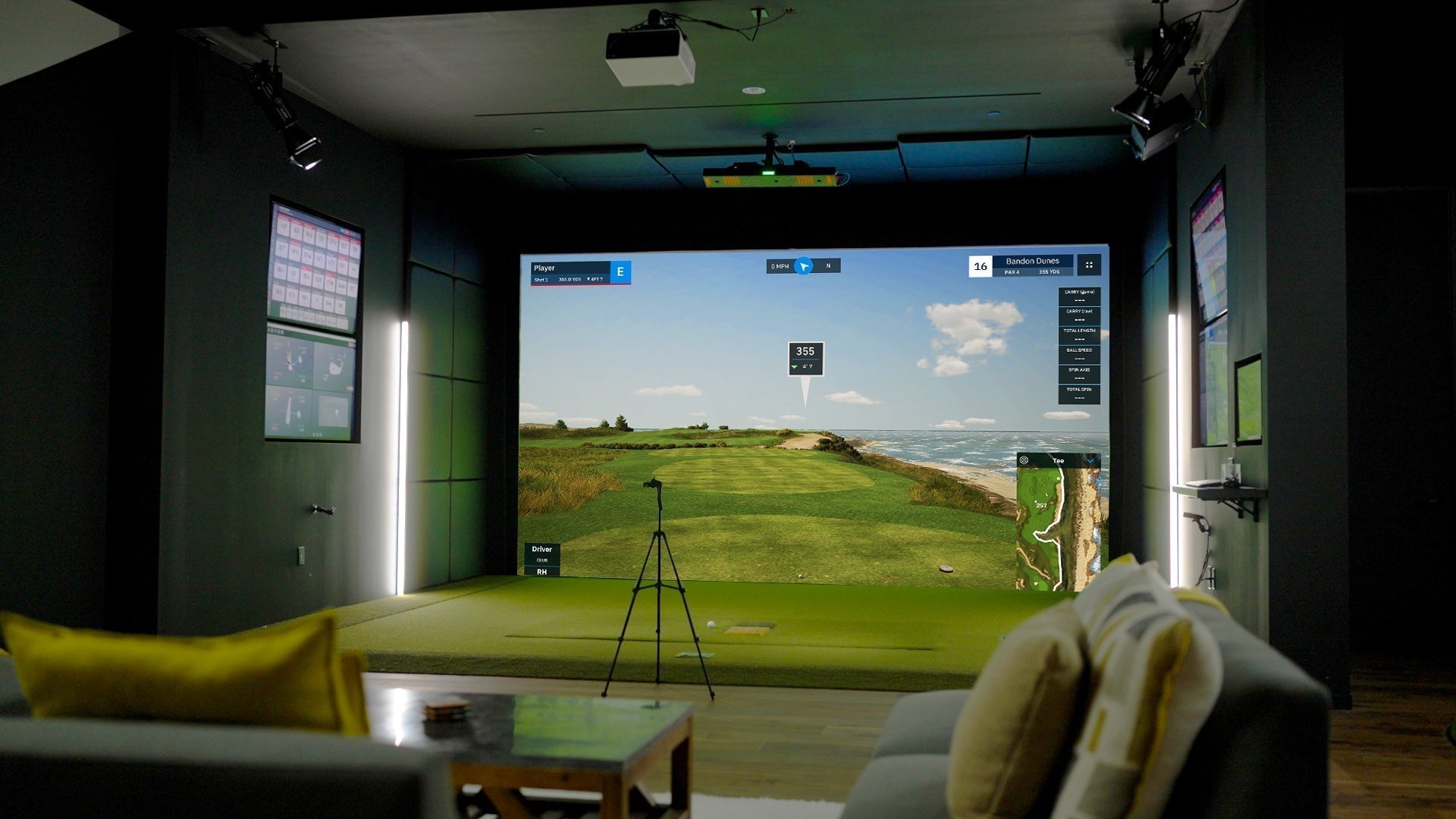 A Uneekor Eye XO2 golf simulator with virtual golf on the impact screen and some furniture in front of it