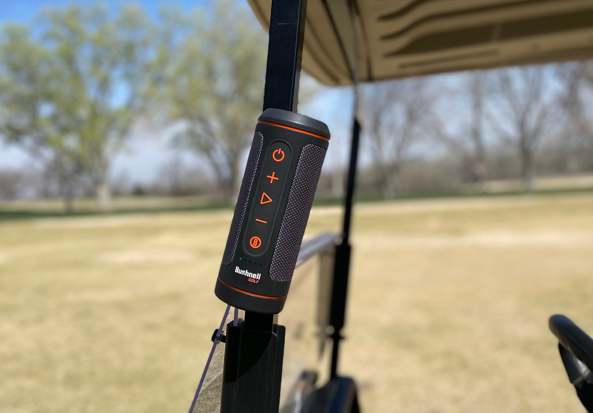The Bushnell Wingman 2 golf speaker attached to a golf cart pole with the device's magnet