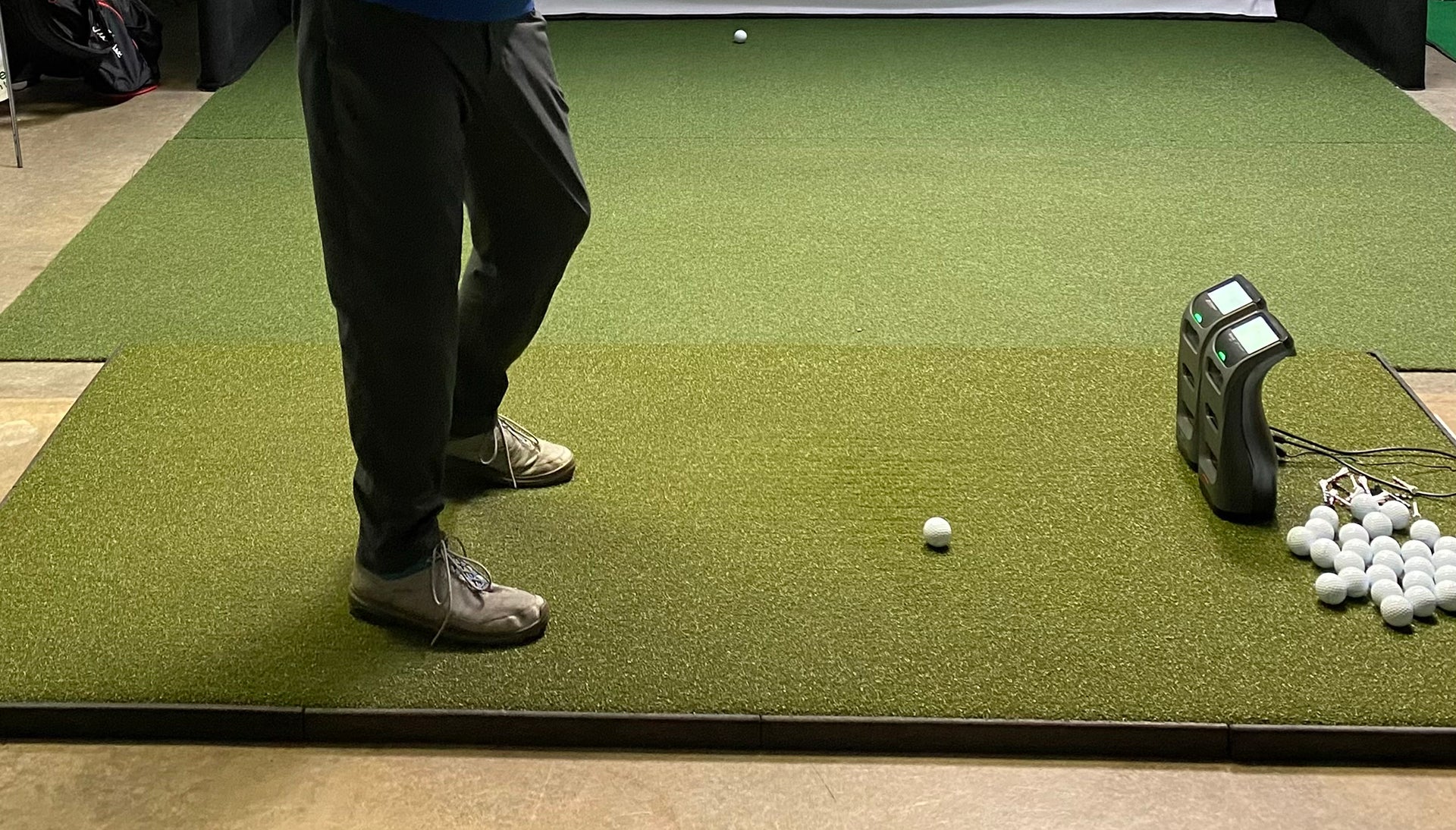 Golfer standing on a Fiberbuilt golf hitting mat in an indoor golf simulator