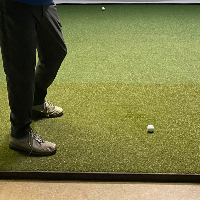 Golfer standing on a Fiberbuilt golf hitting mat in an indoor golf simulator