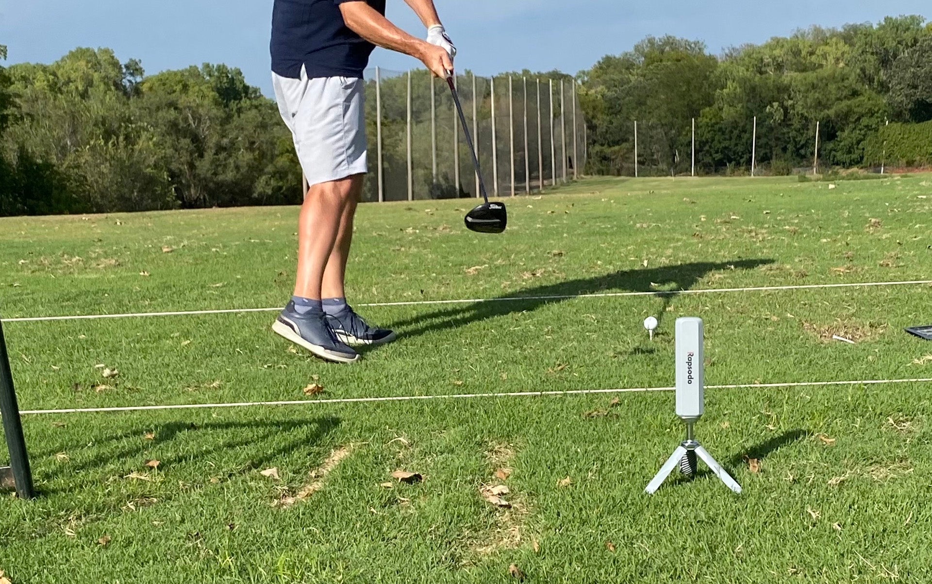 Marc's lower torso on the golf range in mid-swing in front of the Rapsodo MLM2PRO golf launch monitor