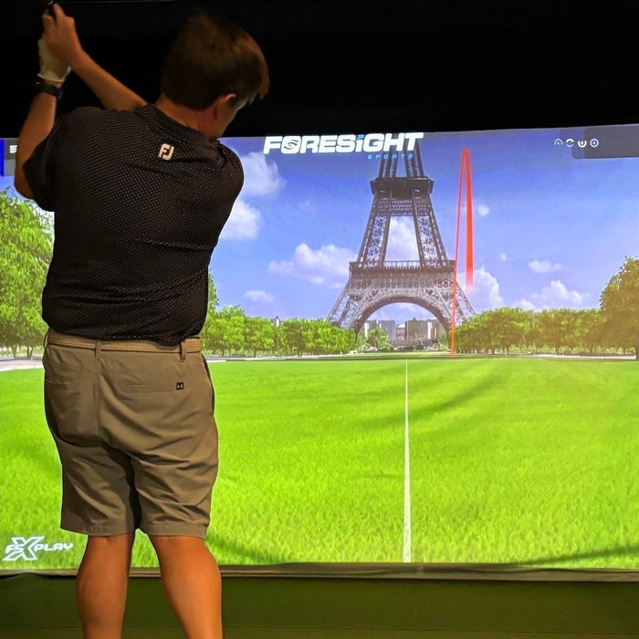 Marc post swing in a golf simulator playing Foresight Sports virtual golf 