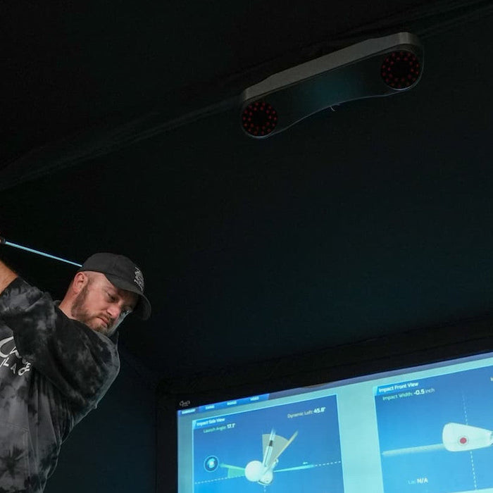 A golfer getting ready to swing in a golf simulator with a ProTee VX golf launch monitor