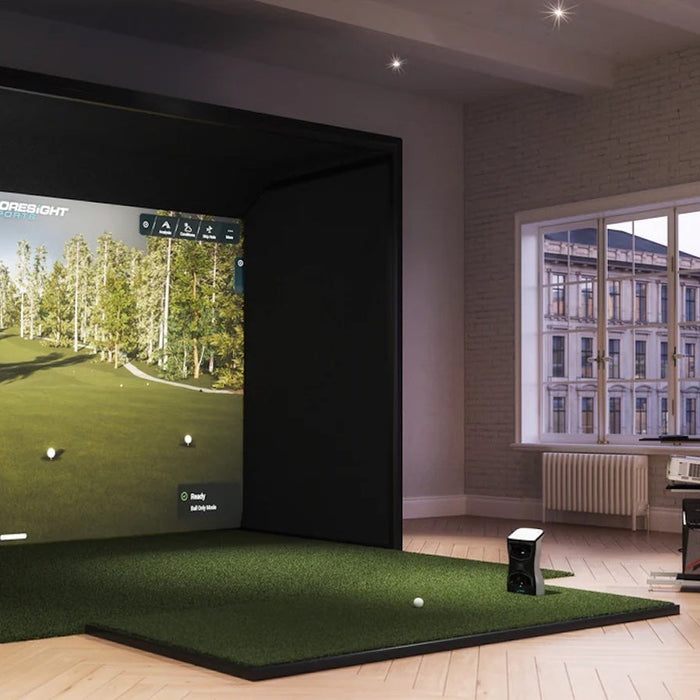 The Foresight Sports QuadMAX launch monitor in an indoor golf simulator in a room with large windows in the city and a sofa