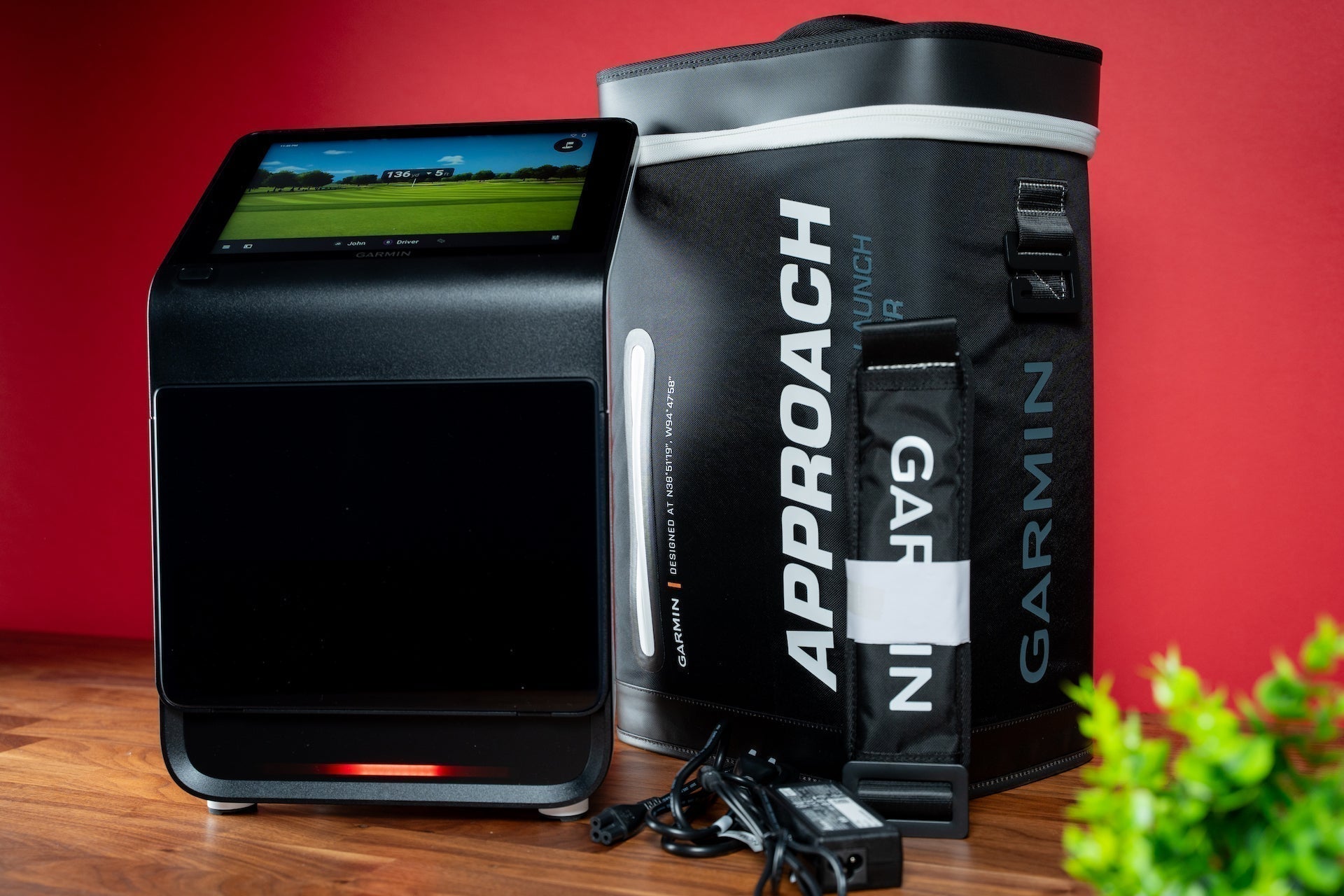 A Certified Pre-Owned Garmin Approach R50 Golf Launch Monitor with its carry case against a red background