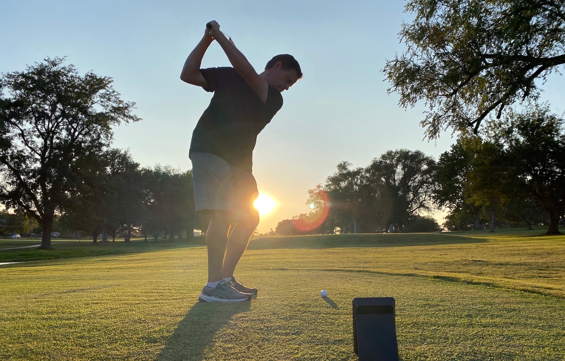 Golf reviewer Marc swinging at sunset on the golf range with the Swing Caddie SC4 behind him