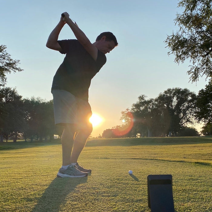 Golf reviewer Marc swinging at sunset on the golf range with the Swing Caddie SC4 behind him