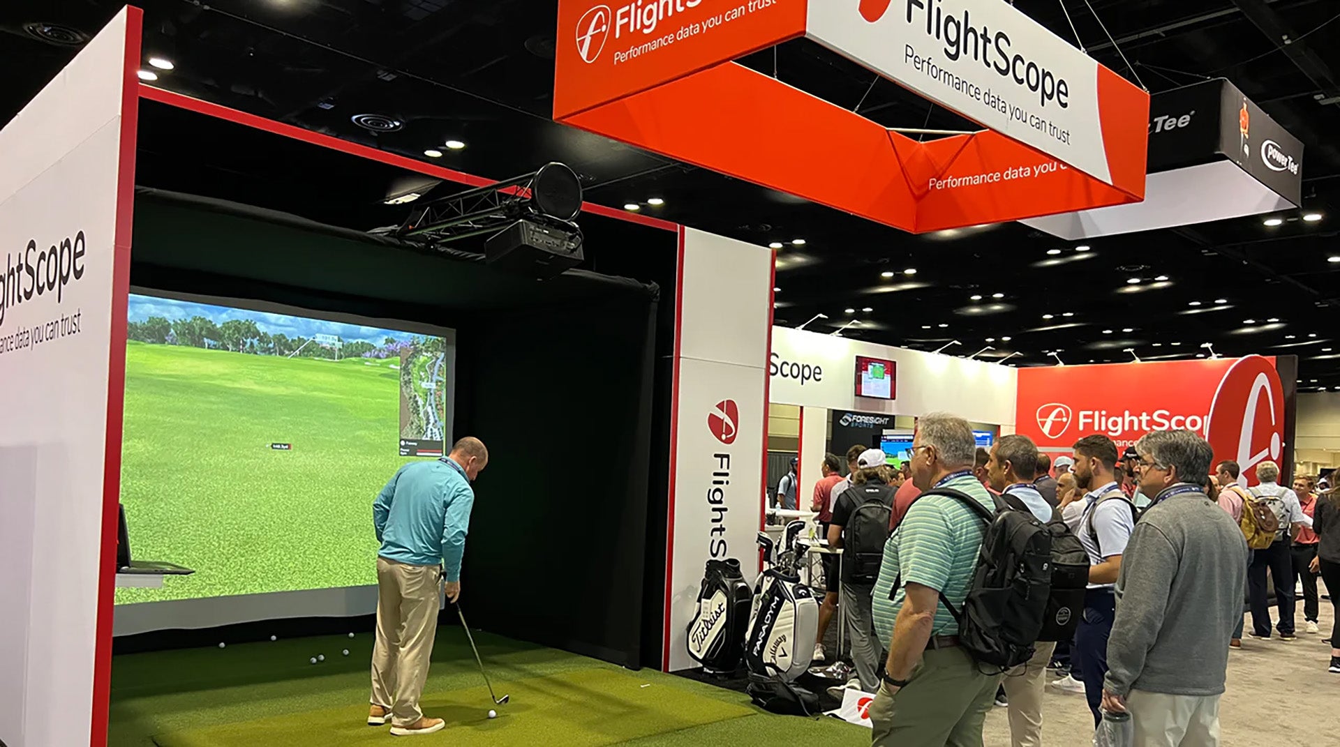 People gathered around the FlightScope golf simulator and display area at the 2024 PGA Show