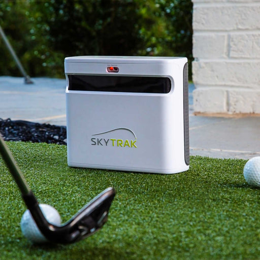 skytrak+ golf simulator and golf launch monitor sitting next to ball waiting to be hit in indoor home golf studio