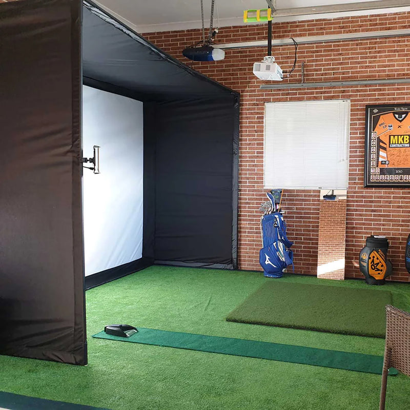 A PlayBetter SimStudio Package set up in a home golf simulator showing enclosure, impact screen, projector, golf hitting mats, golf clubs and decor