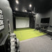Vanish SportScreen retractable golf enclosure and impact screen in a garage with golf club bag, projector and mount, and golf hitting mat.