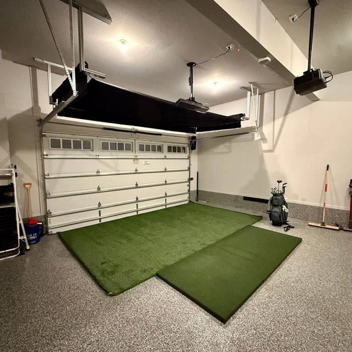 The Blue Tees Rainmaker launch monitor and golf simulator with the remote propped next to it