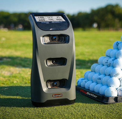 bushnell launch pro golf simulator & launch monitor sitting on a golf driving range in front of some golf balls